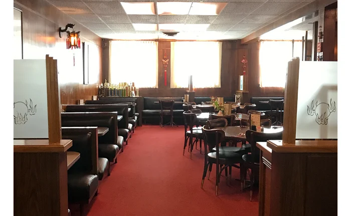The dining room at Eng’s: dark wooden booths, red carpet, white tablecloths, daylight through the front windows.